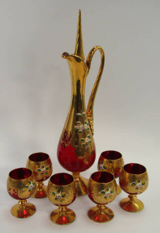 A Bohemian ruby glass liqueur set, of baluster form with gilt overlay and enamel floral decoration, comprising decanter and stopper and six balloon glasses.