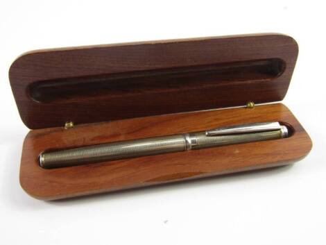 A silver cased cartridge pen, with engine turned decoration, wooden boxed.