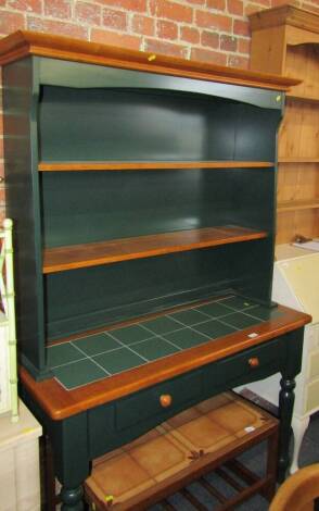 A green painted dresser, with tiled top over two central doors with plate rack top.