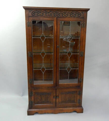 A reproduction carved linen fold oak display cabinet, with two leaded glazed doors, 88cm wide, 34cm deep, 157cm high