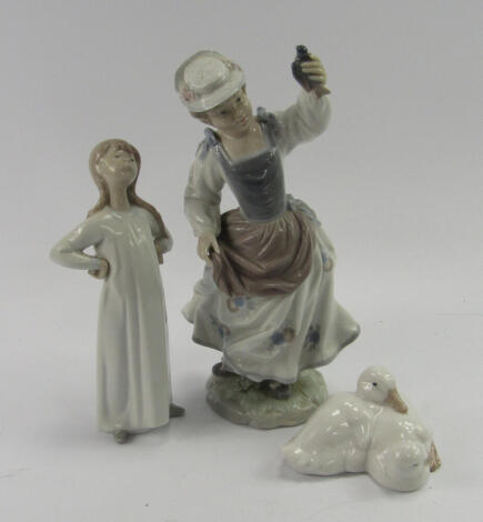 A Lladro porcelain figure of a lady, modelled standing holding a bird in her hand, 25.5cm high, together with a Nao figure of a girl stretching, and a pair of ducklings, (4).