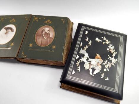 A Chinse lacquer bound photograph album, overlaid to cover in mother of pearl with an eagle in a tree, and a Victorian black leather bound album with tooled butterfly and meadow flower decorations, containing portrait photographs, (2).