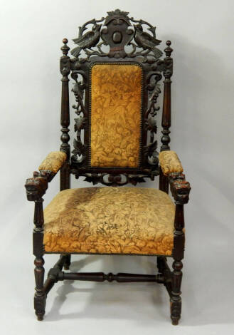 A Victorian oak carver chair, the crest rail carved with a shield and bird supporters, padded back in a surround of vines and fluted columns, padded arms with lion's head terminals, and overstuffed seat, raised on fluted and turned legs united by a H fram