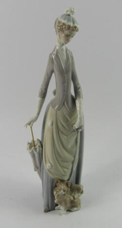 A Lladro porecelain figure of a lady, with a parasol and Pekingese dog, 35.5cm high.