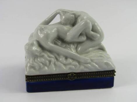 A Continental porcelain box, and hinged cover of rectangular form modelled with deux lesbiennes qui font l'amour, brass hinge and mounts, 10.5cm x 7cm x 9.5cm.