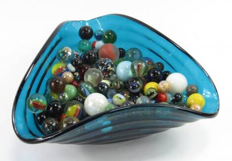 Marbles, (a quantity), in a triform blue glass dish.