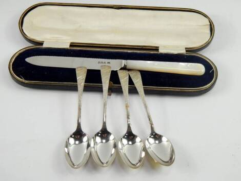 A George V silver bread knife, with mother of pearl handle, Sheffield 1917, cased and four teaspoons with monogram and bright cut engraving, 1.735t oz.