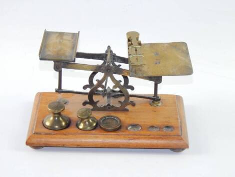 A set of sovereign scales, and a set of brass postal scales, with three weights, raised on a wooden base, (2).