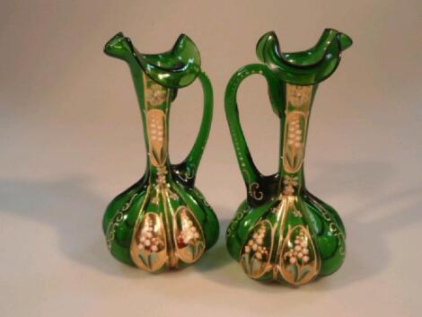 A pair of 19thC green glass ewers with lobed bodies