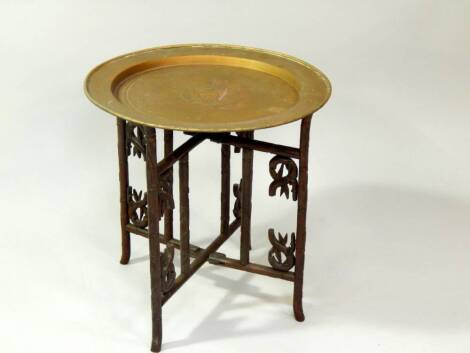 A Benares brass tray top table, with folding and carved base, 56cm dia.