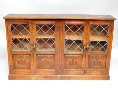 A reproduction oak glazed bookcase, with leaded glazed and gothic arch carved doors, 142cm