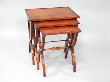 A mahogany nest of x-framed tables, largest 58cm x 56cm x 38cm.