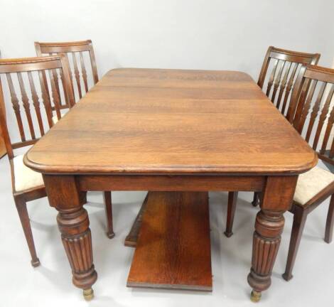 A Victorian oak extending dining table, with moulded top and reeded legs 108cm wide x 243 cm max including two leaves, together with four oak single dining chairs.