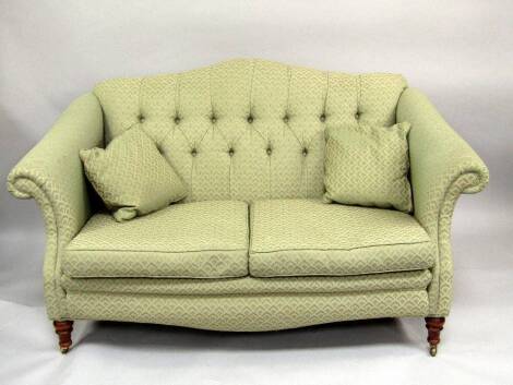 A Victorian style two seater sofa, and matching scroll armchair in green and cream shell upholstery.