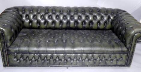 A green buttoned leather Chesterfield sofa.