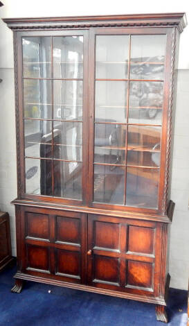 A Waring and Gillows oak cabinet bookcase, with two astragal glazed doors over two panelled door base, and outswept Spanish feet, 112cm wide, 190cm high.