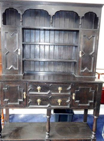 An early 20thC Jacobean style oak dresser, with plate rack and cupboard top, moulded drawers and doors, baluster legs and pot board, 153cm wide, 50cm deep, 218cm high.