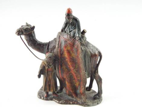 A cold painted metal figural table lighter, of a carpet seller on his camel in the manner of Bergman, a further figure standing on a naturalistic base, 18cm high, (AF).