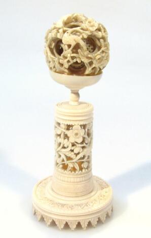 A Qing period Chinese ivory puzzle ball, probably late 19thC, on removable stand, the orb top heavily carved with bamboo and other leaves with at least three inner sections, on a part pierced cylindrical base terminating in a decorative foot, 17cm high.