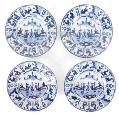 A set of four Dutch 17thC Delft ware dishes, decorated in blue and white with figures centrally under a canopy, within a border of repeating panels of stylised flowers and figures, 22.5cm diameter.