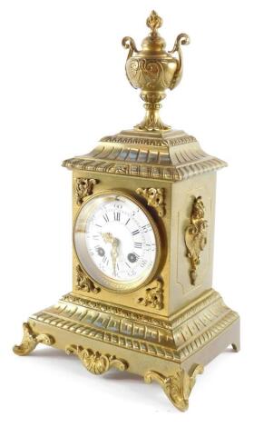 A late 19thC French brass cased mantel clock, circular enamel dial bearing Roman and Arabic numerals, eight day movement with bell strike by A Chapus, 86 Rue de Rivoli., the case embossed with masks and scrolls, with twin handled urn finial, raised on a s