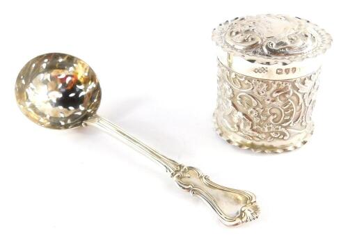 A Victorian silver sugar sifting spoon, Thomas Smily, London 1862, and a Victorian silver dressing table jar and cover, embossed with putti and rococo scrolls, shield reserve, Army & Navy Co-Operative Society Ltd, London 1894, 2.76oz. (2)