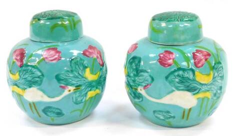 A pair of Chinese turquoise glaze ginger jars and covers, moulded in relief with birds and water lilies, in the style of Wang Bing, 11cm high.