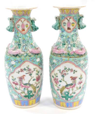 A pair of Chinese Republic 20thC porcelain vases, famille rose decorated with reserves of Ho Ho birds and flowers, moulded with lizards and lion dogs, against a turquoise ground sgraffito decorated with flowers, red six character seal mark, 26cm high.