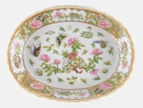 A Chinese Republic Cantonese famille rose oval porcelain dish, painted with flowers, butterflies, and Buddhistic symbols, red four character seal mark, 29cm wide.