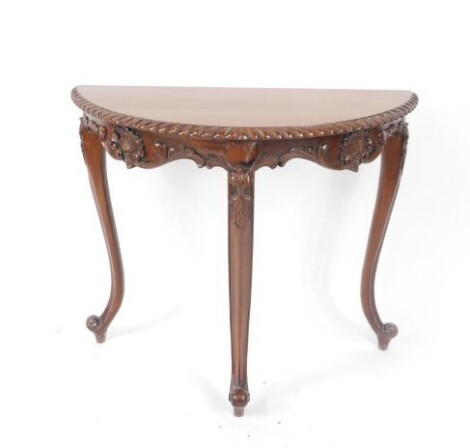 A Victorian style mahogany demi lune console table, with foliate and shell carving, raised on slender cabriole legs, 75cm high, 88cm wide, 39cm deep.