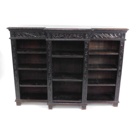 A Victorian oak breakfront bookcase, with a foliate carved frieze, and eight shelves, raised on block feet, 113cm high, 153cm wide, 36cm deep.