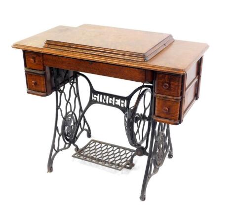 A Singer oak table cased treadle sewing machine, the machine decorated with Egyptianesque motifs, no F7977451, the table with one long and four short drawers, raised on a cast iron base, 78cm high, 92cm wide, 45.5cm deep.