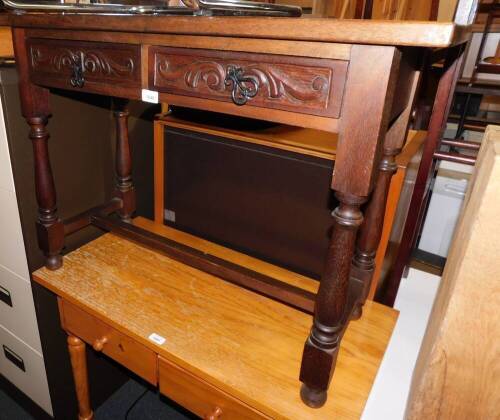 A mahogany two drawer side table, with carved drawer fronts, raised on turned legs, 70cm high, 95cm wide, 39cm deep.