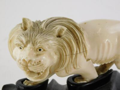 A 19thC oriental carved ivory figure of a prowling lion, (AF), 16cm long, on contemporary hardwood stand. - 2