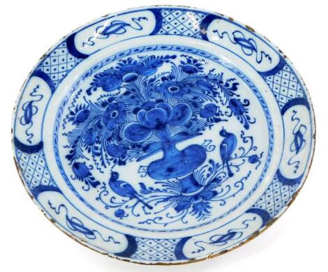 An 18thC English Delft plate, decorated with a basket of flowers, birds, etc., in blue within borders of scrolls etc., in the Chinese manner, (AF), 34.5cm diameter.