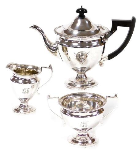 A late 19thC silver plated three piece tea service, comprising tea pot, milk jug and sugar bowl, the teapot with an ebony knop and handle, on a fluted baluster stem, makers stamp MH & Co, each piece by W Mantle and company, and bearing the initials CF, th