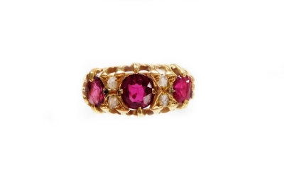 A ruby and diamond set gypsy ring, set with three oval rubies, and four tiny diamonds, each in claw settings yellow metal stamped 18ct, ring size J, 2.9g all in.