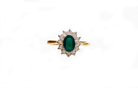 A modern dress ring, formed as a cluster set with green and white paste stones, on a gold plated band, ring size K.