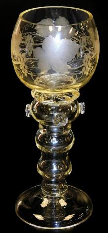 An early 20thC hock glass, the balloon bowl with grapevine and leaf decoration, on a baluster stem with prunts, on plain foot, on a yellowy finish, 18cm high.