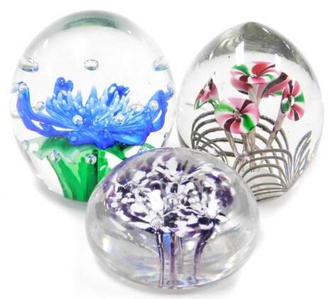 Three paperweights, each of floral decoration, the blue flower 12cm high, the pink and green five stemmed flower, 11cm high, and the purple flower 10cm diameter. (3)