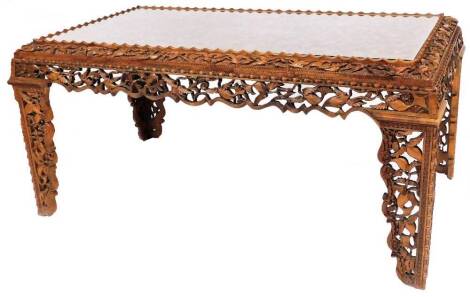 A late 20thC Eastern hardwood dining room table, the design heavily carved with storks and flowers, with rectangular top with central oval floral panel with glass inset top on a raised edge, on shaped legs 80cm high, 163cm wide, 90cm deep.