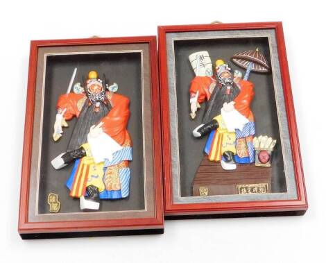A pair of modern Chinese wall art pictures, each depicting characters from the Peking Opera, in raised 3D design in glass display case with red coloured lacquer border, 35cm x 21cm. (2)