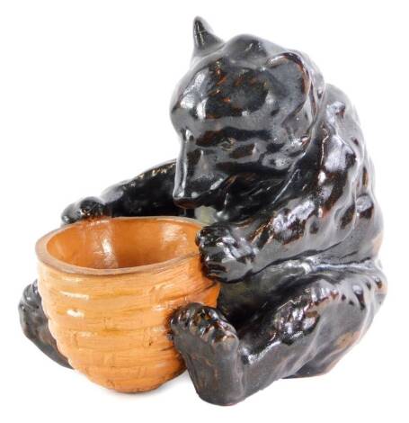 A Royal Doulton stoneware salt, modelled in the form of bear or bear cub, holding a basket in the manner of Mark V Marshall, impressed marks to underside, 9cm high.