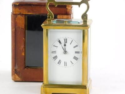 A brass carriage clock, with hour repeat, the white enamel dial with Roman numerals, the case with a swing handle, in leather travelling case with key, the clock 15cm high overall. - 2