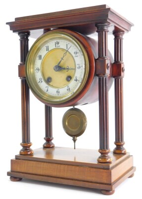 A late 19th/early 20thC French walnut portico clock, with a moulded top, reeded pillars supporting a clock with white enamel dial, Arabic numbers on a plinth with bun feet, 30cm high, 21cm wide.