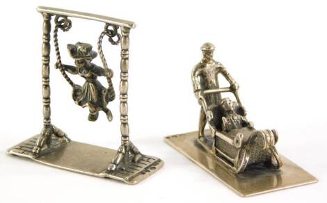 Two Dutch miniature figures, one of a girl on a swing, and another of a man pushing a sleigh, white metal. (2)