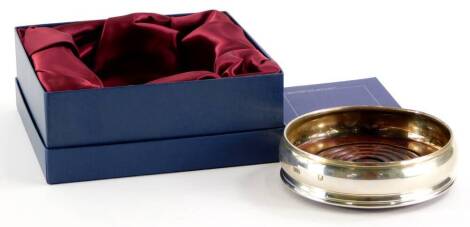 An Elizabeth II silver wine coaster, on a turned wooden base, London 2001, 13cm diameter, boxed.