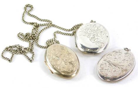 Three silver oval lockets, each with engraved floral design, one on a silver curb link chain.