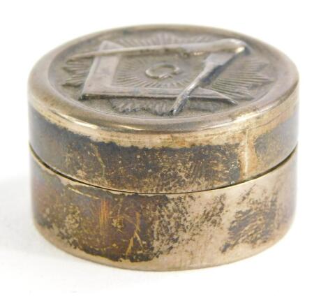 A silver white metal pill box, the hinged lid decorated with Masonic motifs to include angle, compass, etc., 2¾cm diameter.