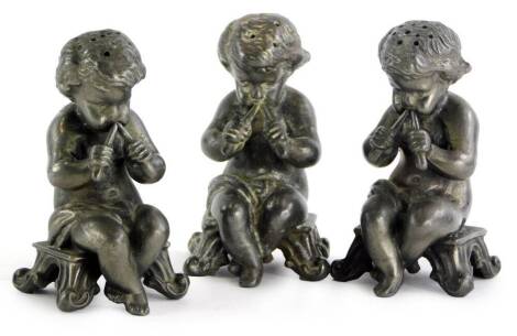 Three cast pewter putti cruets, each seated on a stool.